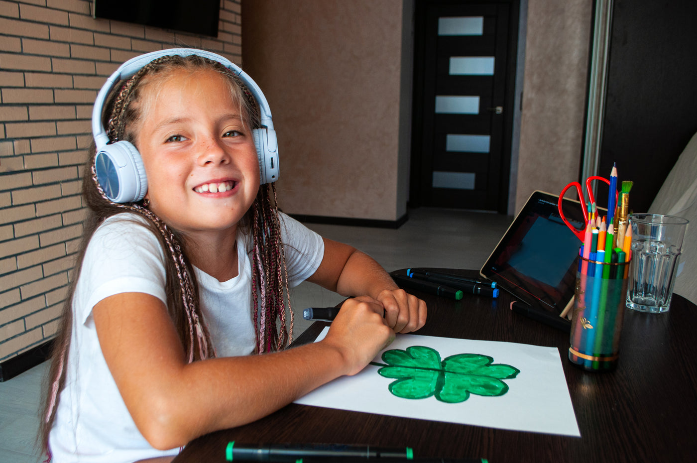 Child having a sensory brain break in school. Student wearing ear defenders headphones and drawing in class for sensory needs. Child with sensory processing disorder colouring in class