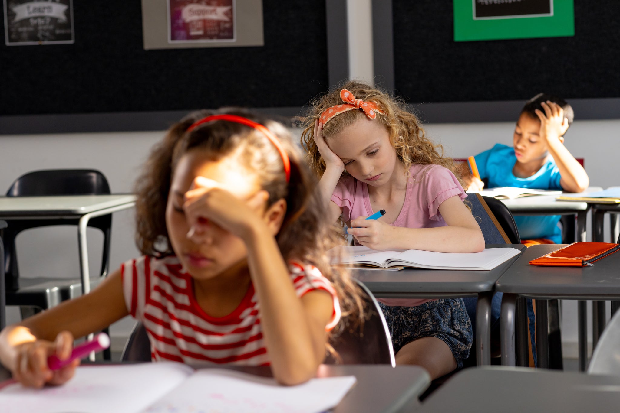 Children slumped, distracted and not listening in school. Finding it difficult to sit still and write: students needing to move in the classroom. 